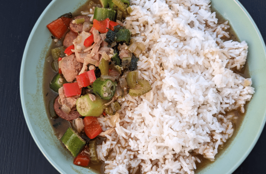 chicken gumbo and white rice in a pale green bowl on a black background