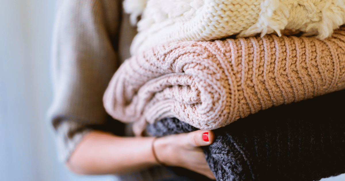 woman holding folded sweaters